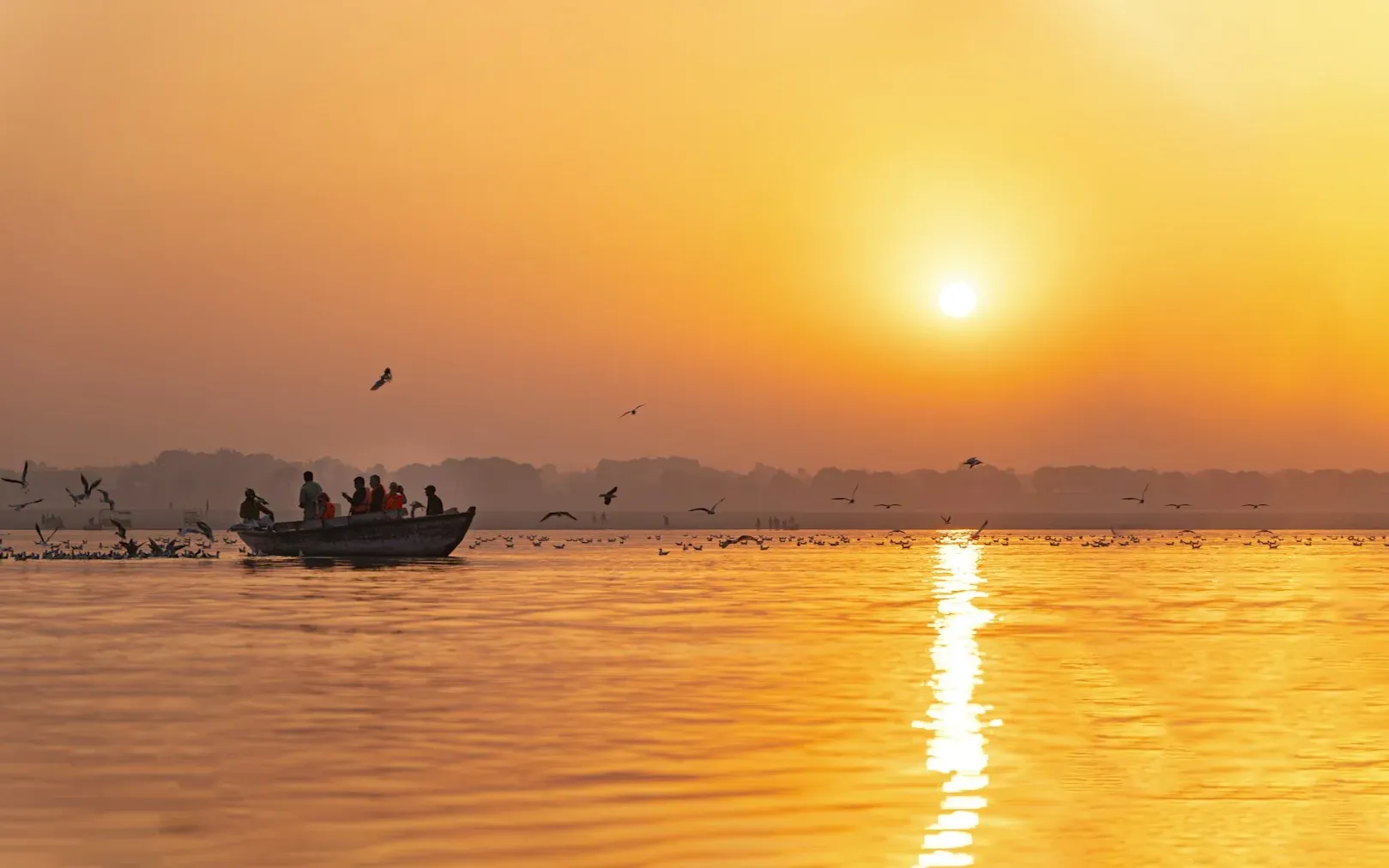 Une barque et des oiseaux sur le Gange à Varanasi au lever du jour