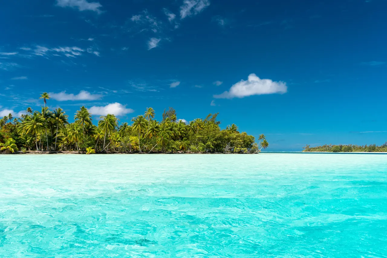 Motu bordé de cocotiers dans le lagon turquoise de Huahine